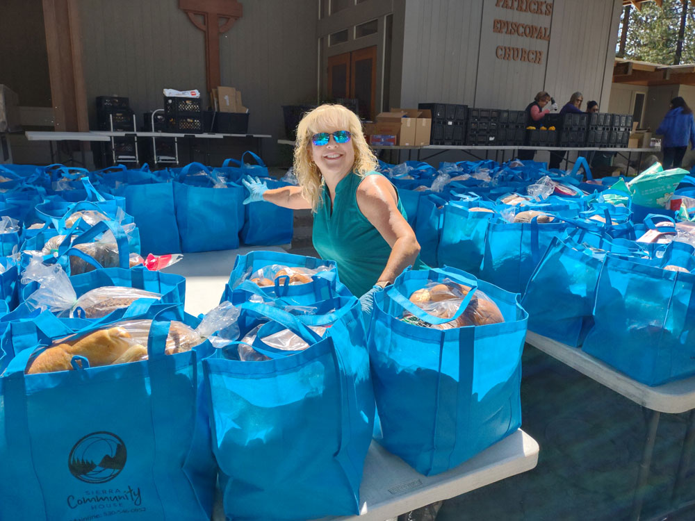 Woman helping with a food drive surrounded by bags of food