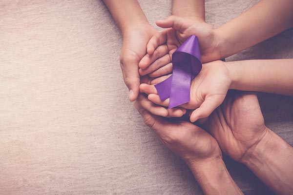 hands-holding-purple-ribbon Hands holding a purple ribbon representing domestic violence awareness