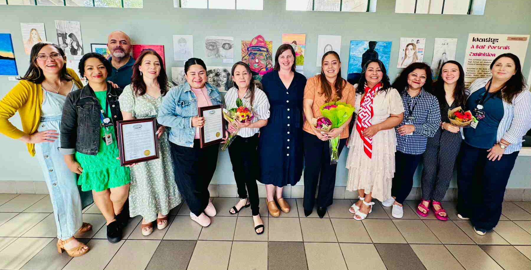 group of people stand together with certificates and bouquets